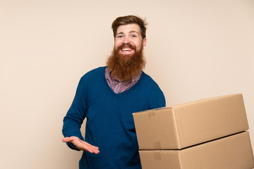 Redhead man with long beard over isolated background holding a box to move it to another site