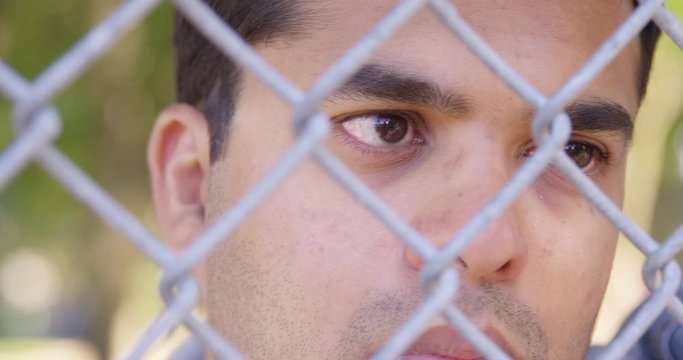 Close Up - Pan to Indian man staring longingly through a chain fence - Slow Motion - shot on RED