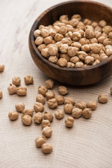 chickpeas scattered from bowl on beige wooden table