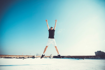 Young attractive man jumping in the air on the roof of a residential building