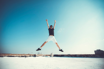 Young attractive man jumping in the air on the roof of a residential building