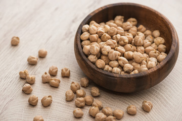 chickpeas scattered from bowl on beige wooden table