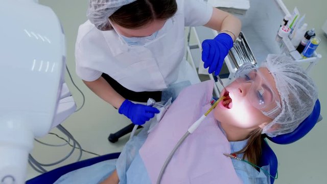 Stomatology treatment in clinic. Dentist pour water on woman teeth use saliva ejector during ultrasound cleaning to watch best. Dental oral hygiene ultrasonic brushing procedure in dentistry.