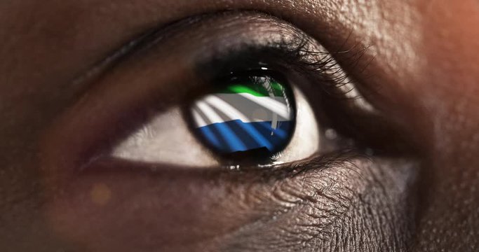 Woman black eye in close up with the flag of Sierra leone in iris with wind motion. video concept