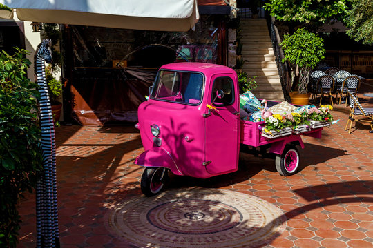 A small three-wheeled car stands on the empty street