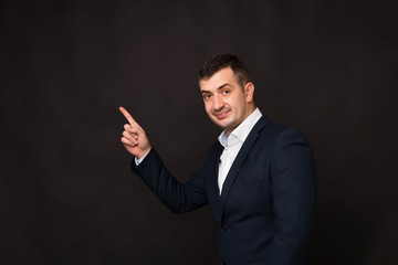 Photo of businessman, wearing formal clothes, pointing away up at copy space