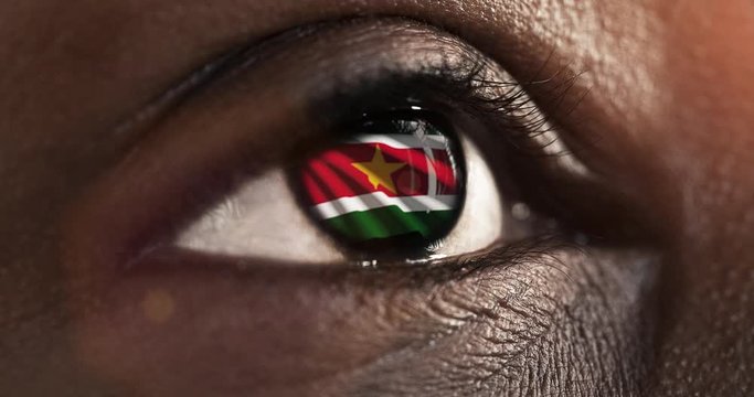 Woman black eye in close up with the flag of Suriname in iris with wind motion. video concept