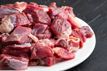 Pieces of raw meat on a white plate close-up
