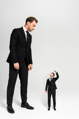 businessman in suit looking at marionette showing fist on grey background