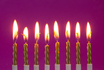 Burning golden candles on purple background