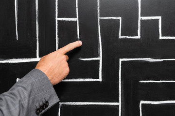 cropped view of businessman in suit pointing with finger at labyrinth