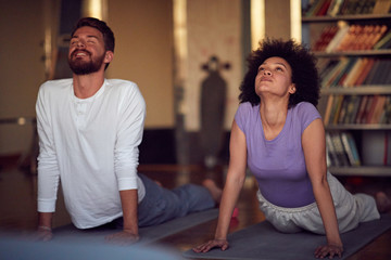 Fototapeta na wymiar .Man and woman exercising doing yoga together at home