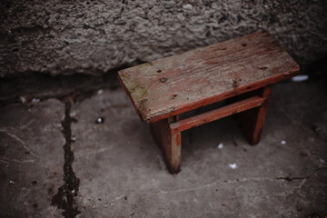 old small wooden chair in a rural yard by the wall.