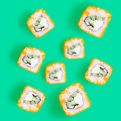 Rolls with cucumber, crab meat and tobiko caviar on a green background. The effect of flight, levitation. Top view, minimalism. Japanese food concept.