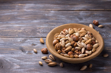 Variety of nuts in wooden bowl over wooden table. almonds, walnuts, hazelnuts, pistachios. rustic style. horizontal	