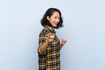 Asian young woman over isolated blue background pointing to the front and smiling