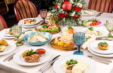 Served for holiday banquet restaurant table with dishes, snack, salads, cutlery, wine and water glasses. European food in a restaurant setting. Table set for an event party. catering
