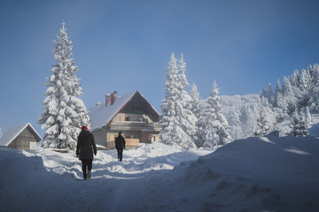 People walking towards a mountain hut on a cold winter day.