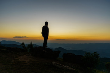 silhouette of man on top of mountain at sunset