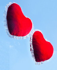 Two red heart shaped cushions against the sky