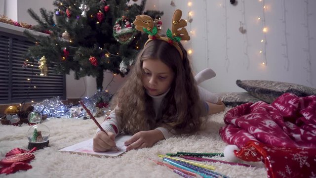 beautiful girl neatly draws a pencil drawing of Santa Claus. Preparing for the new year.