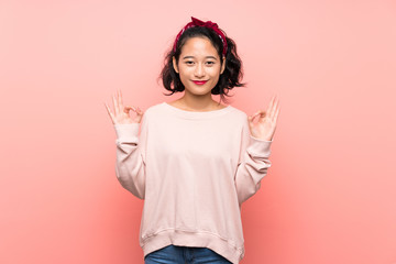 Asian young woman over isolated pink background in zen pose