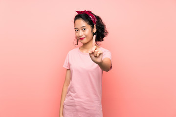 Asian young woman over isolated pink background showing and lifting a finger