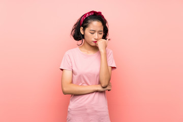 Asian young woman over isolated pink background having doubts