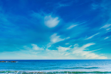 Beautiful clean blue sky, clouds, sea or ocean and waves at the beach in sunny day at summer time season. Sea and sky background. 
