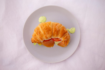 croissant sandwich of a salmon and avocado and the tomato