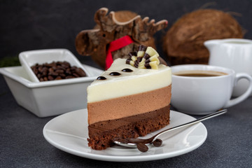 Three chocolate mousse cake on a small plate. A trio of milk, dark and white chocolate combined in a delectable mousse.