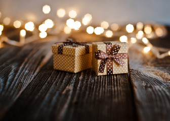 Christmas gift box lay on a wooden table on a background bokeh of festive lights.