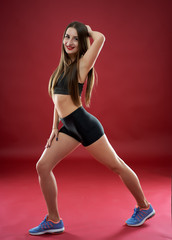 Fitness model doing workout on red background