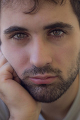 Fototapeta premium Close-up of caucasian boy with beard and clear eyes. Sad, severe, hard expression. Focus on the eyes
