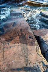 ancient rock carvings petroglyphs on the shore of Onega Lake carved on a granite plate . Age of object - 5000-6000 years. Cape Besov Nos, Karelia, Russia.