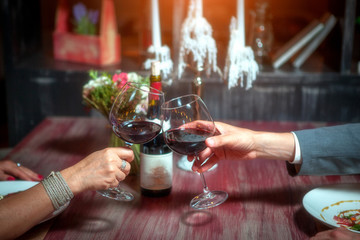 romantic couple with glasses of red wine on a date in a cozy Italian restaurant. Leisure, drinks, people and holidays concept - happy man and woman clinking glasses.