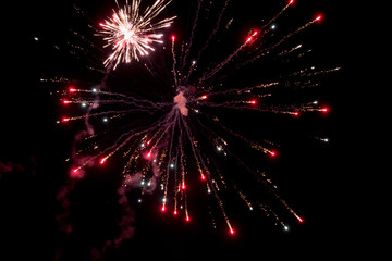 Fototapeta na wymiar A few volleys of festive fireworks in the night sky, red-yellow.