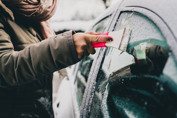 Fototapeta Hands of a woman seen cleaning a frosty window on a car. Early morning cleaning of iced car windows obraz