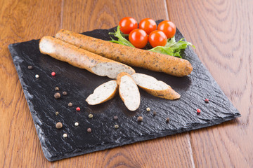 chiken sausages with cherry tomatoes and herbs on a slate board