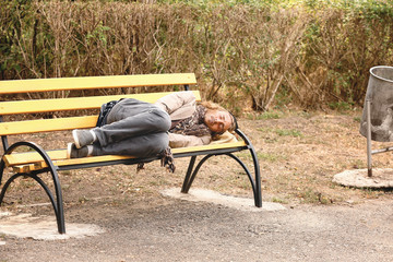 Poor homeless man sleeping on bench outdoors