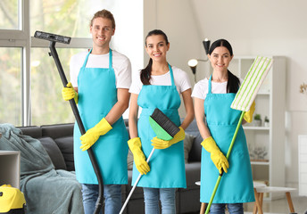 Team of janitors with cleaning supplies in room