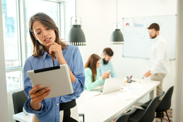 Fototapeta premium Young woman using tablet. In modern office team people work on new project