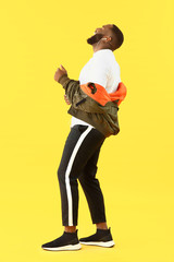 Emotional African-American man listening to music on color background