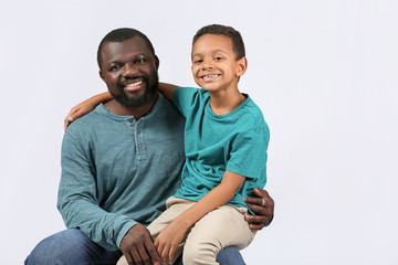 Obraz premium Portrait of African-American man with his little son on light background