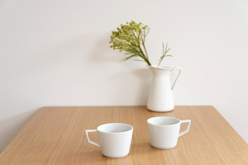 白いマグカップと白い花瓶　観葉植物のあるテーブル　木製　木目　木　ナチュラル　インテリア　イメージ　部屋　室内　おしゃれ　カフェ　お茶　