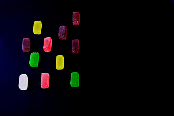 Multi-colored marshmallows under sugar close-up. Food photo of sweets and desserts on a dark background
