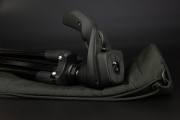 Universal tripod for camera and camcorder lies on a black background.