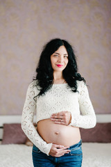 Waiting baby. Pregnant woman standing and hands embraces a round belly, stomach. close-up. nine months. Baby Shower. Motherhood concept. front view.