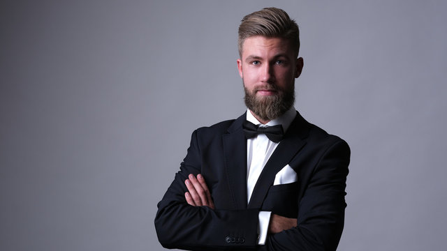 Handsome caucasian man with beard in classic black suit.