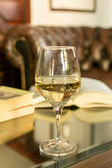 English retro style room with leather chair, open book and glas of white wine